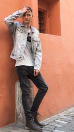 Full length portrait of boy standing against wall