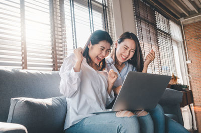 Young women using laptop while sitting on sofa at home