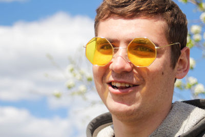 Portrait of young woman wearing sunglasses against sky