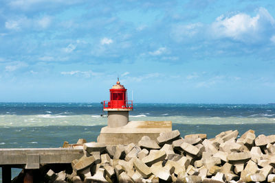 Lighthouse by sea against sky