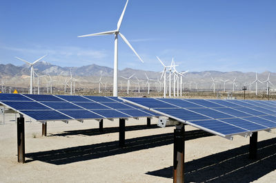 Wind turbines on land against blue sky