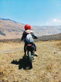 Rear view of man riding motorcycle on field