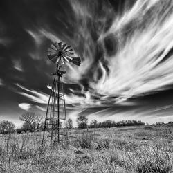 Low angle view of wind turbines on field