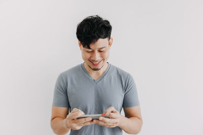 Young man using smart phone against white background