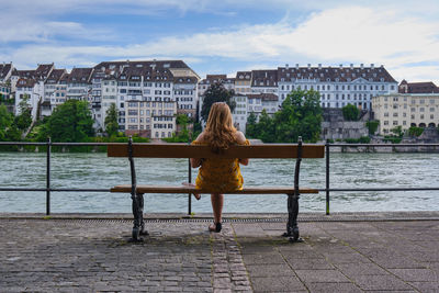Rear view of woman standing by river in city