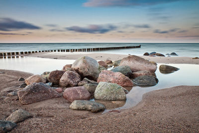 Rocks on beach against sky during sunset