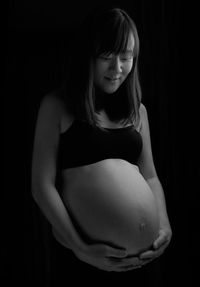 Close-up of a smiling young woman against black background