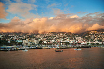 Aerial view of townscape by sea against sky