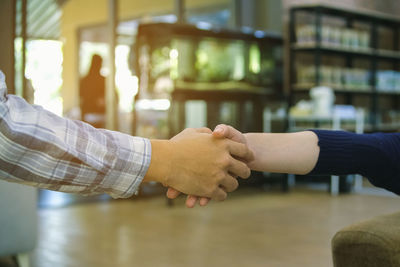 Cropped image of business people giving handshake at cafe