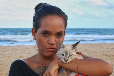 Portrait of young woman with cat on beach