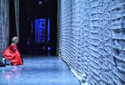 Side view of woman sitting in corridor