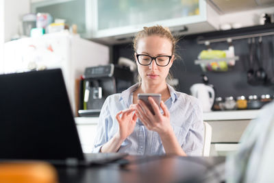 Smiling woman holding mobile sitting at home