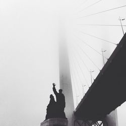 Low angle view of silhouette man using mobile phone against sky