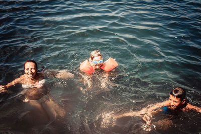 Happy mother and her boys having fun in water during summer day.