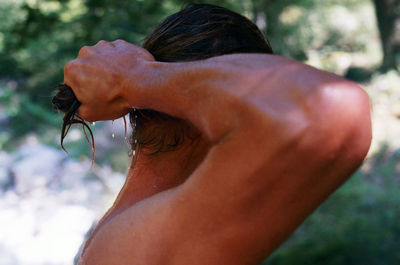 Side view of shirtless wet man with hand in hair