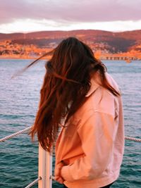 Side view of woman with long hair standing by sea