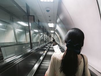 Rear view of woman standing on escalator
