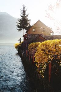 House by lake and trees against sky