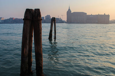 Scenic view of la giudecca with wooden posts at sunset