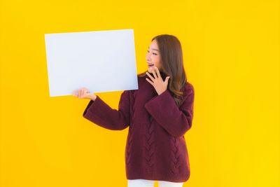 Woman standing against yellow wall