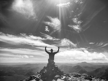 Silhouette woman with arms outstretched against dramatic sky