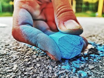 Cropped hand holding chalk on street