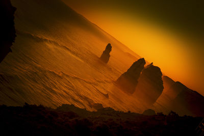 Scenic view of mountain against orange sky