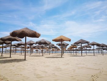 Lounge chairs and umbrellas on beach against sky