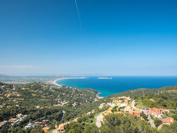 High angle view of townscape by sea against blue sky