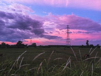 Electricity pylon on field against sky during sunset