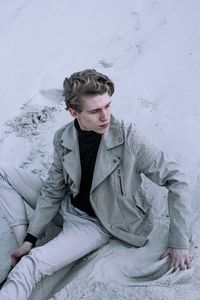 Full length of young woman sitting on snow