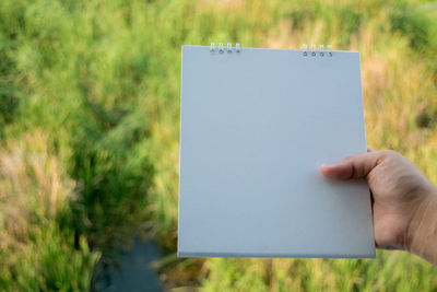 Close-up of hand holding paper on field