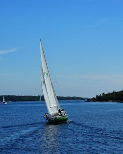 Boat sailing on sea against clear blue sky