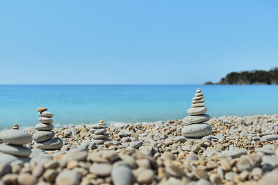 Pyramid stones balance on the beach against the background of the sea and the sky. 