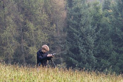 Man with digital camera and tripod in forest