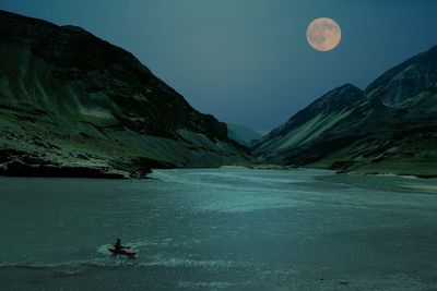 Person swimming in lake amidst mountains against sky