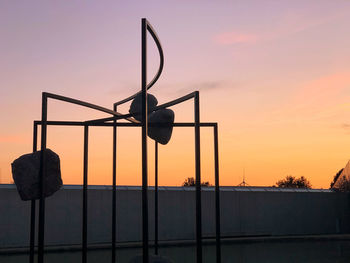 Silhouette cranes against sky during sunset