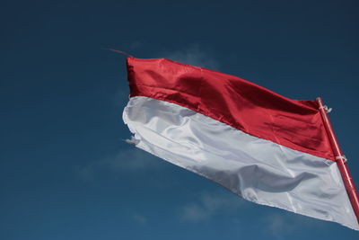 Low angle view of flag against blue sky