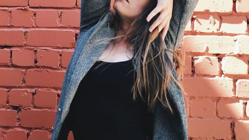 Midsection of woman standing against brick wall