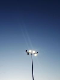 Low angle view of illuminated street light against clear blue sky