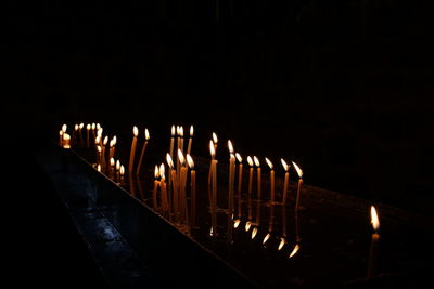 Illuminated candles against black background