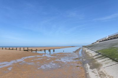 Pier on beach against blue sky