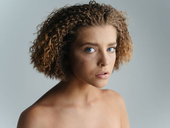 Portrait of shirtless young woman against gray background