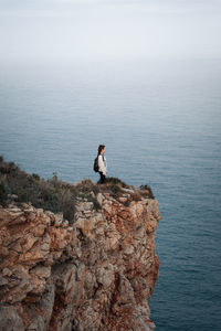 Man standing on rock by sea