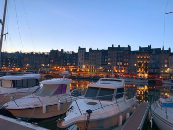 Boats moored at harbor in city against sky during sunset