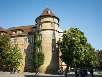 Group of people in front of building against clear blue sky