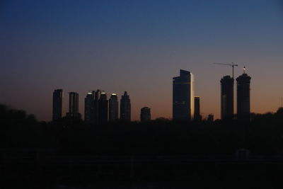 Buildings in city against clear sky during sunset