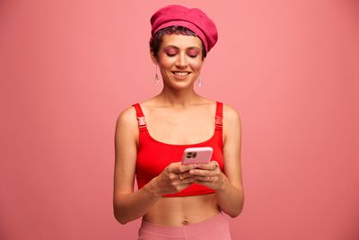 Portrait of young woman holding gift against yellow background