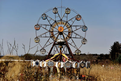 Low angle view of ferris wheel on field against clear sky