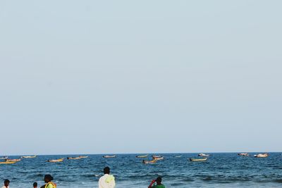 People on sea against clear sky